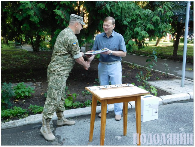 Полковник Володимир Родіков (ліворуч) приймає подарунок від Олега Мельника